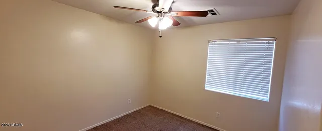 an empty room with a window and a fan