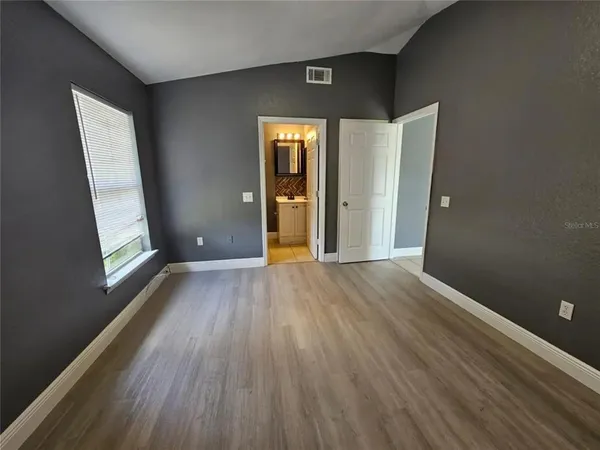 an empty room with wooden floor and windows