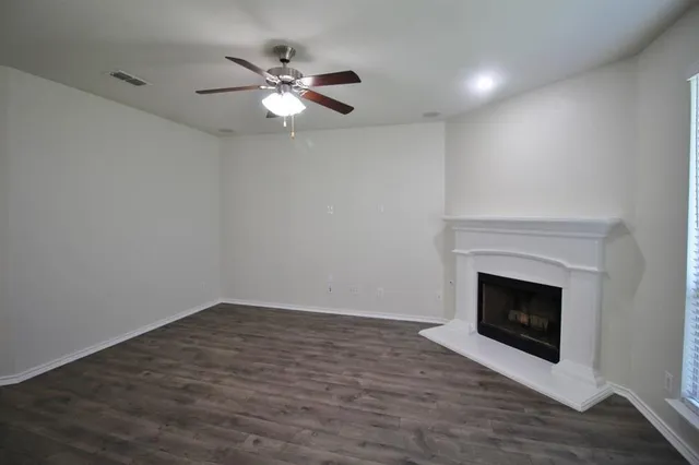 a view of an empty room with wooden floor and fireplace