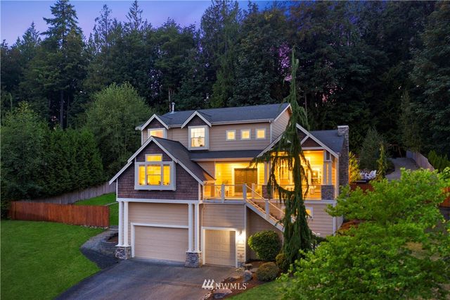 a view of a house with a small yard and large trees