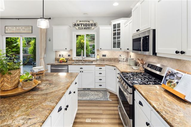 a kitchen with stainless steel appliances granite countertop a stove a sink and a microwave