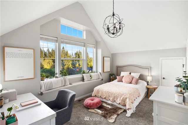 a bedroom with a bed a chandelier and a window