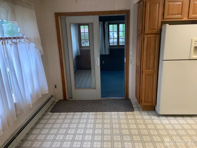 a view of a hallway with wooden floor and a refrigerator