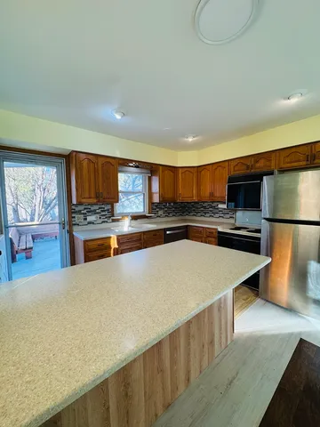 a large kitchen with stainless steel appliances a large counter top a stove and a sink