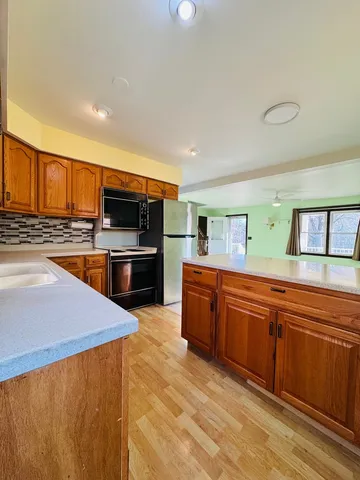 a large kitchen with stainless steel appliances wooden cabinets a stove and a refrigerator