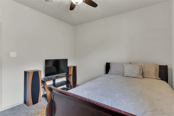 a bedroom with a bed and a flat tv screen on a dresser