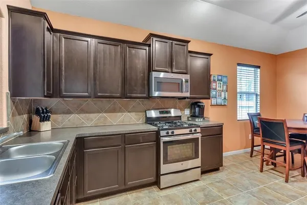 a kitchen with stainless steel appliances granite countertop a stove a sink dishwasher and a microwave oven with cabinets