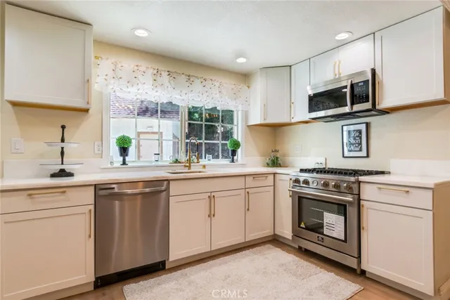 a kitchen with stainless steel appliances granite countertop a stove a sink and a microwave