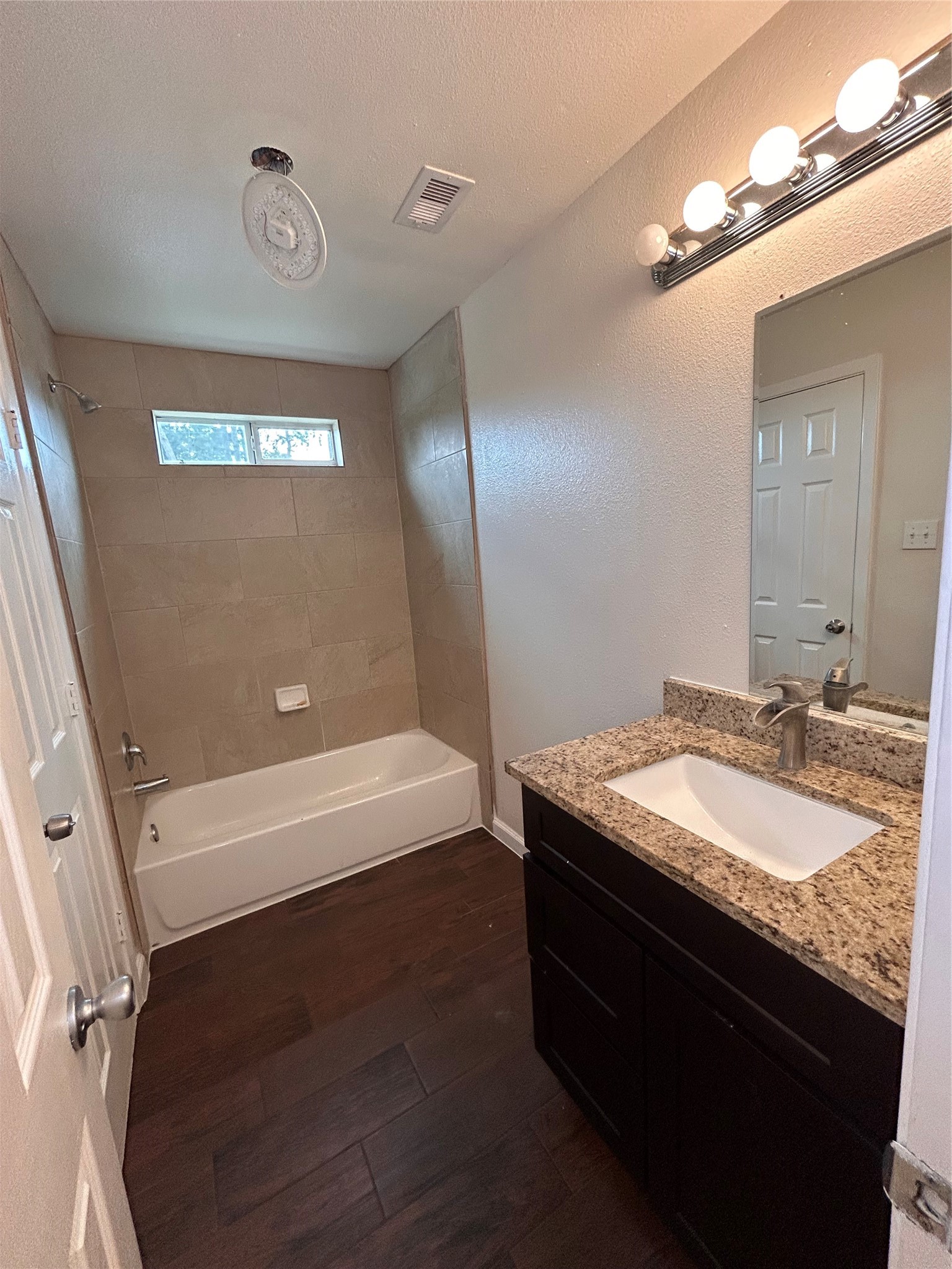 6837 Larkstone Street, Unit A Houston, TX 77028 - Photo 16 of 18 a bathroom with a granite countertop sink a toilet a mirror and bathtub