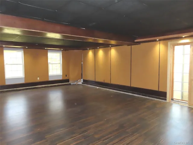 an empty room with wooden floor and windows with curtains