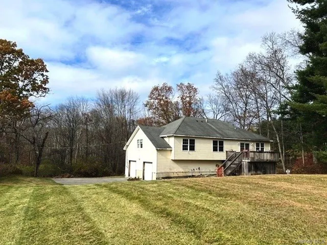 a view of a house with a yard and large trees