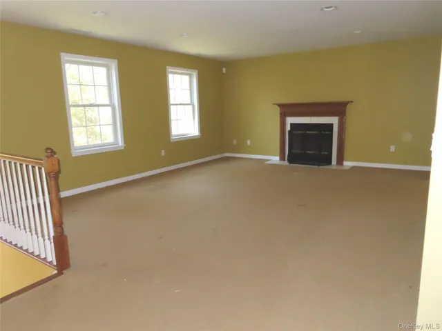 an empty room with windows and fireplace
