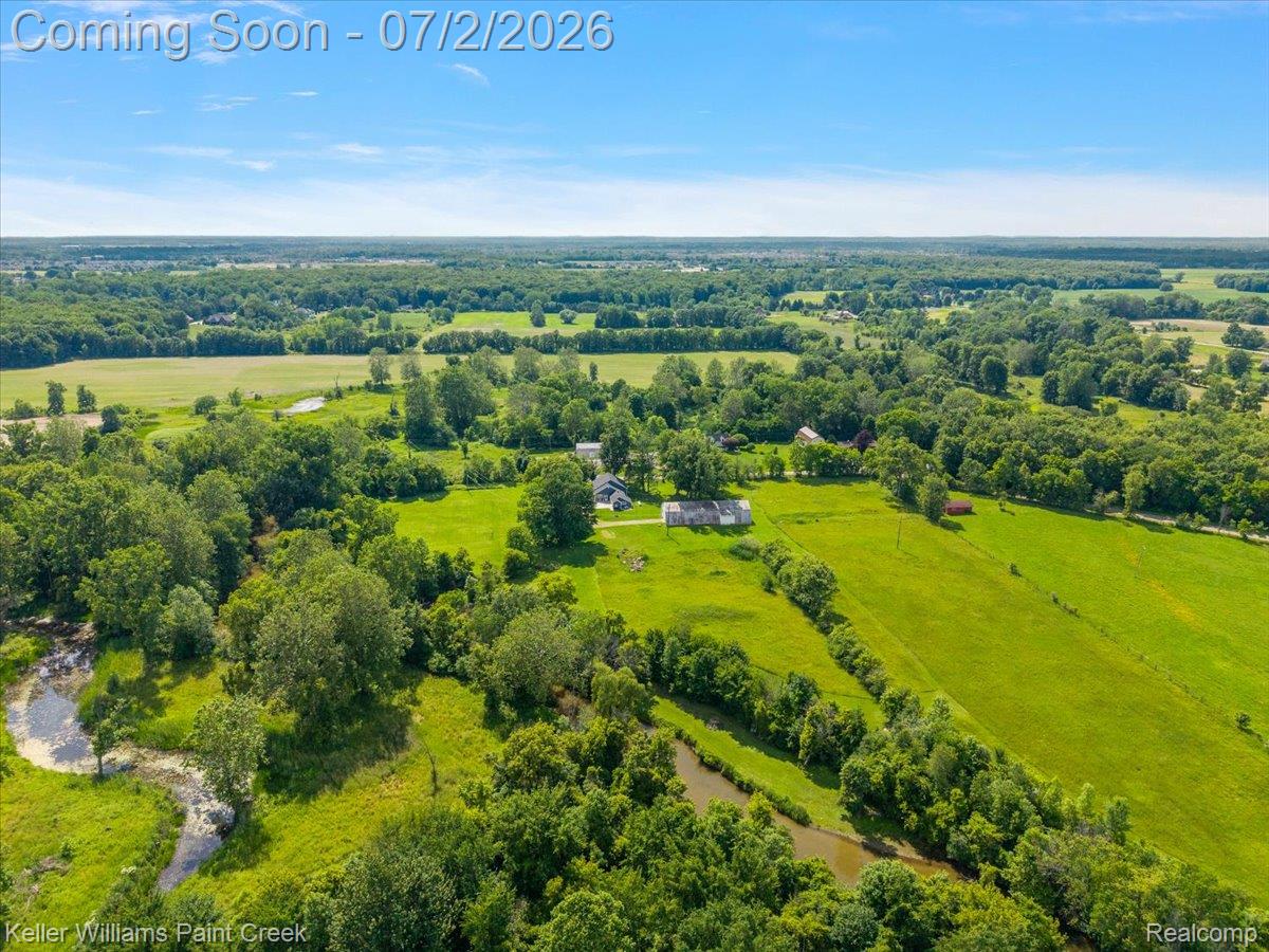 54230 Card Road Macomb, MI 48042 - Photo 27 of 73 Expansive land parcel featuring open fields, mature trees, a natural waterway, and distant structures