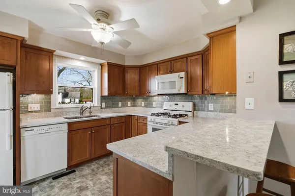 a kitchen with stainless steel appliances granite countertop a sink stove refrigerator and cabinets