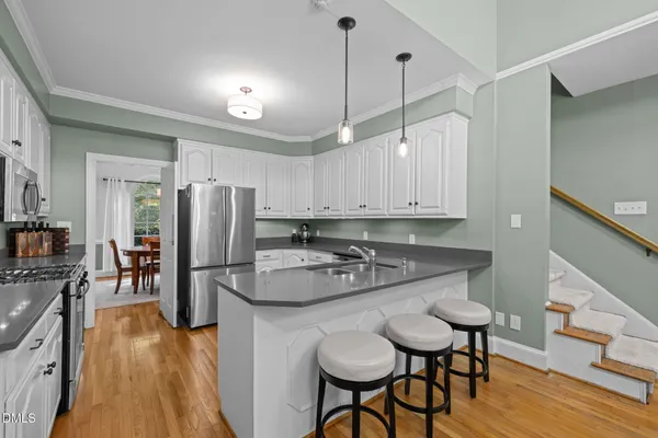 a kitchen with stainless steel appliances granite countertop a sink a stove and chairs
