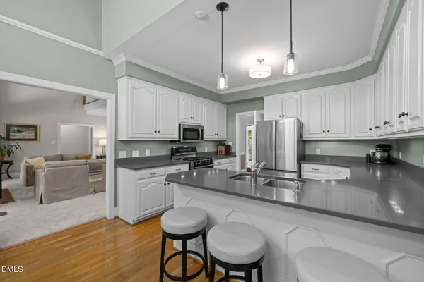 a kitchen with stainless steel appliances granite countertop a sink a stove a refrigerator cabinets and chairs