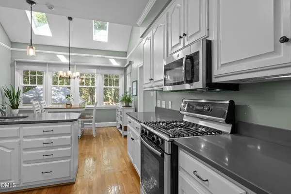 a kitchen with stainless steel appliances white cabinets a sink and a stove