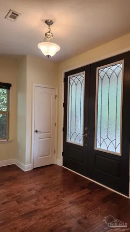 an empty room with wooden floor cabinet and windows