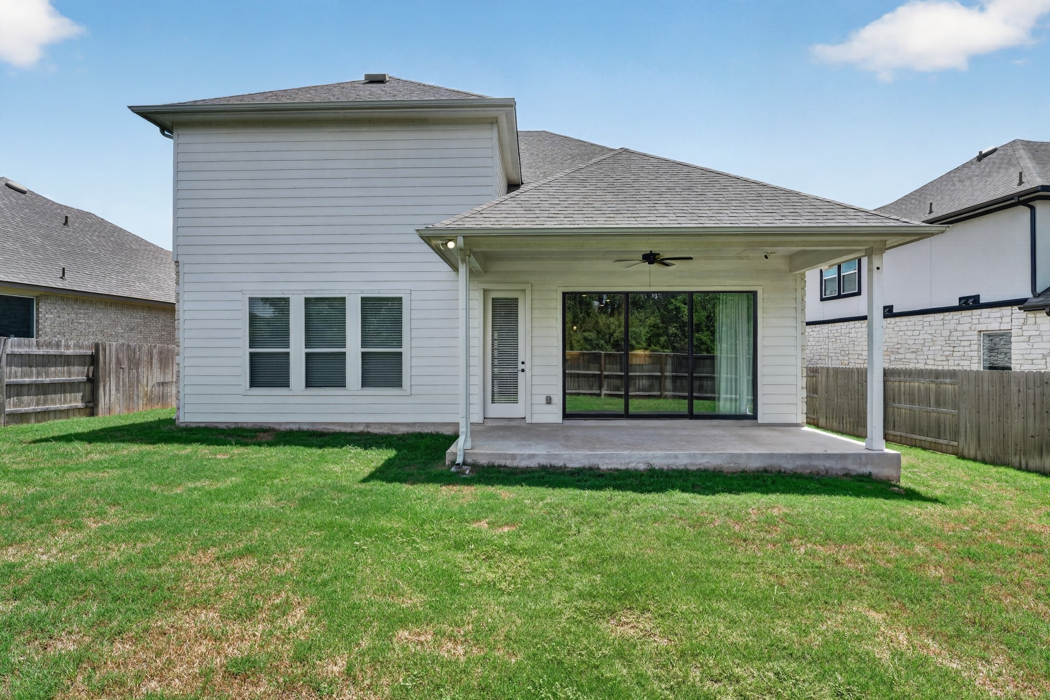 508 Pinnacle View Drive Georgetown, TX 78628 - Photo 24 of 27 A well-maintained lawn stretches behind a residence featuring a covered patio and expansive glass doors.