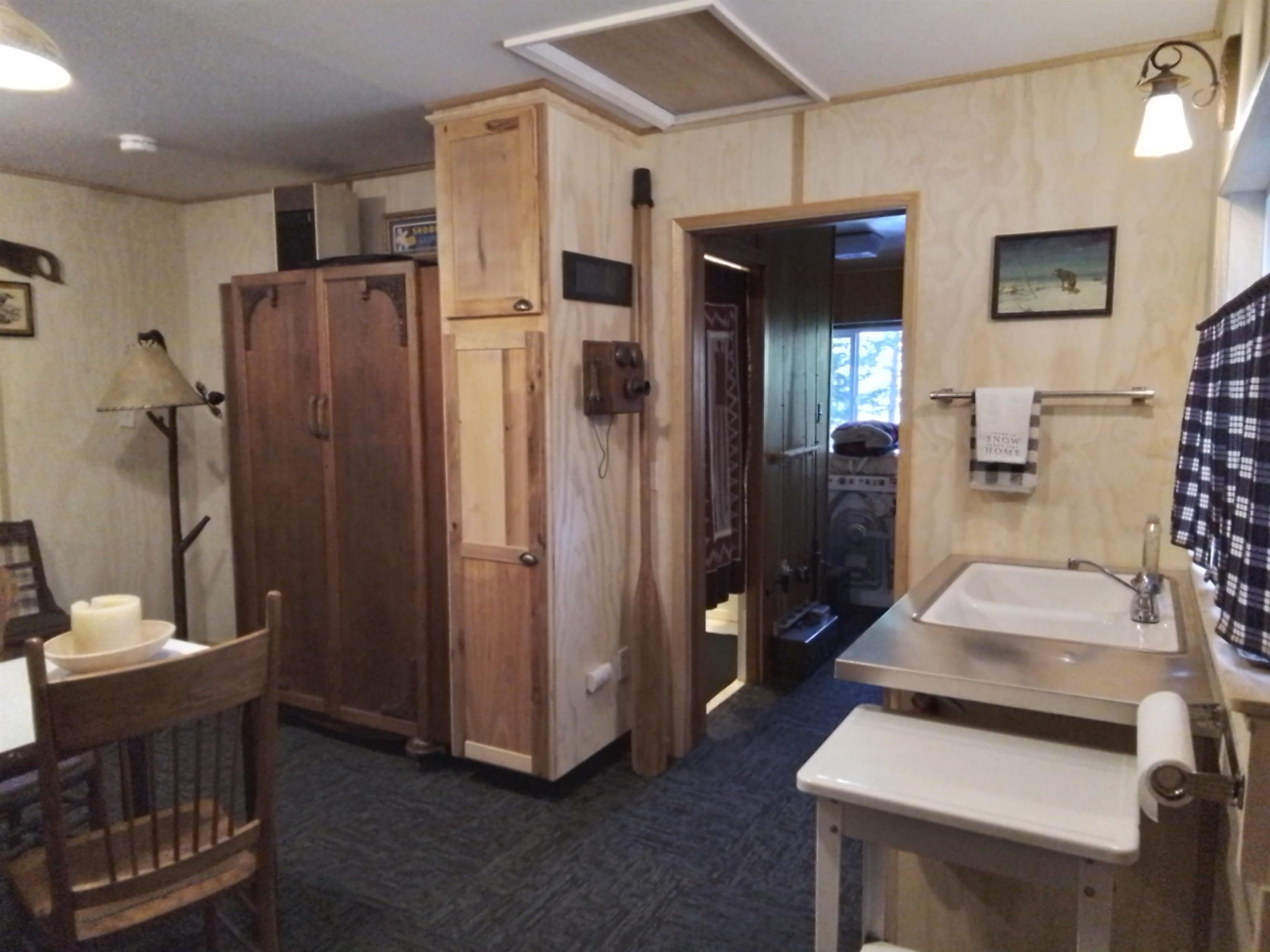 199 Hunewill Drive Bridgeport, CA 93517 - Photo 19 of 40 Compact utility area featuring a stainless steel sink, wood-finish paneling, and dark patterned carp