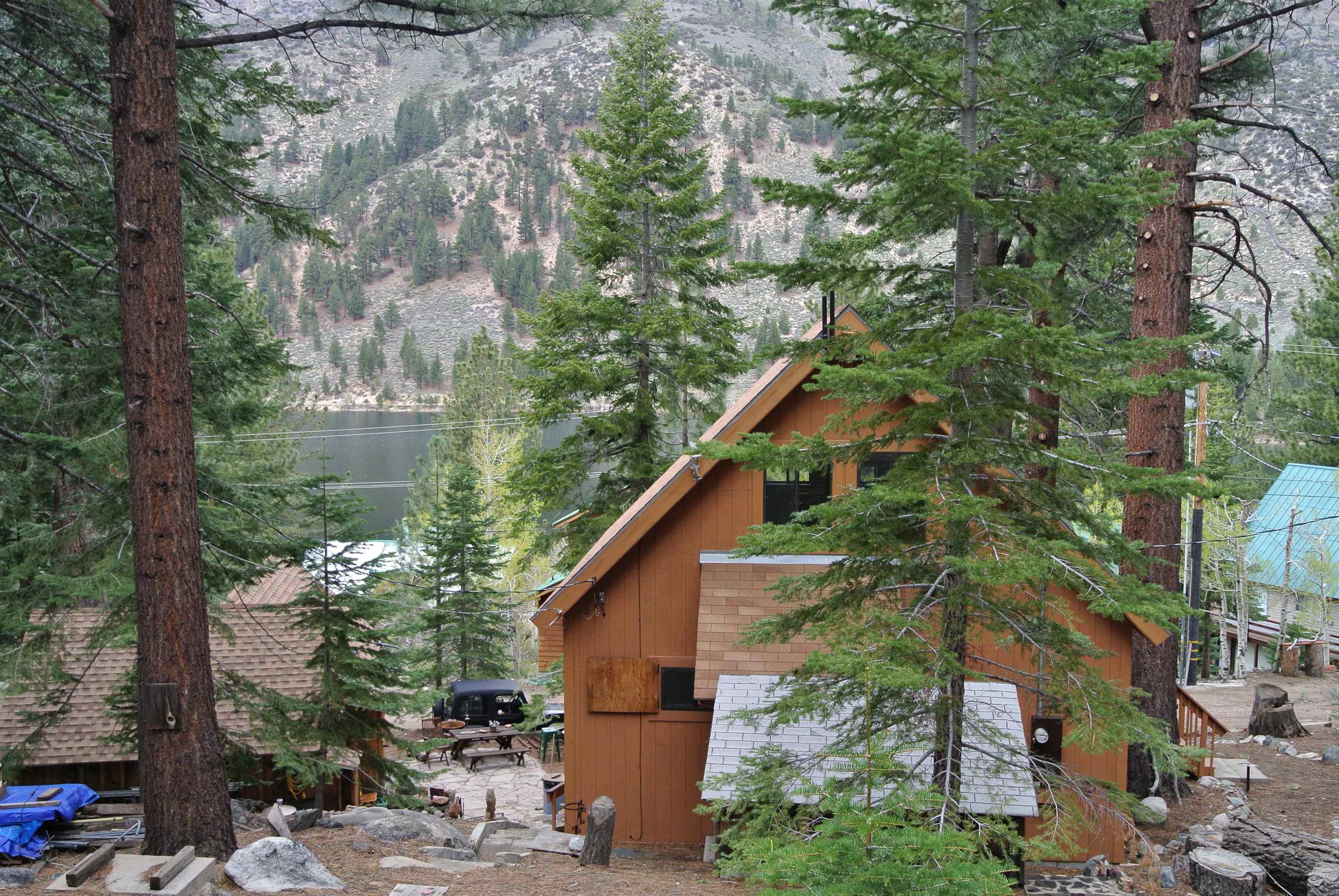 199 Hunewill Drive Bridgeport, CA 93517 - Photo 33 of 40 Wood-sided cabin with an A-frame roof and an elevated deck, surrounded by mature pine trees