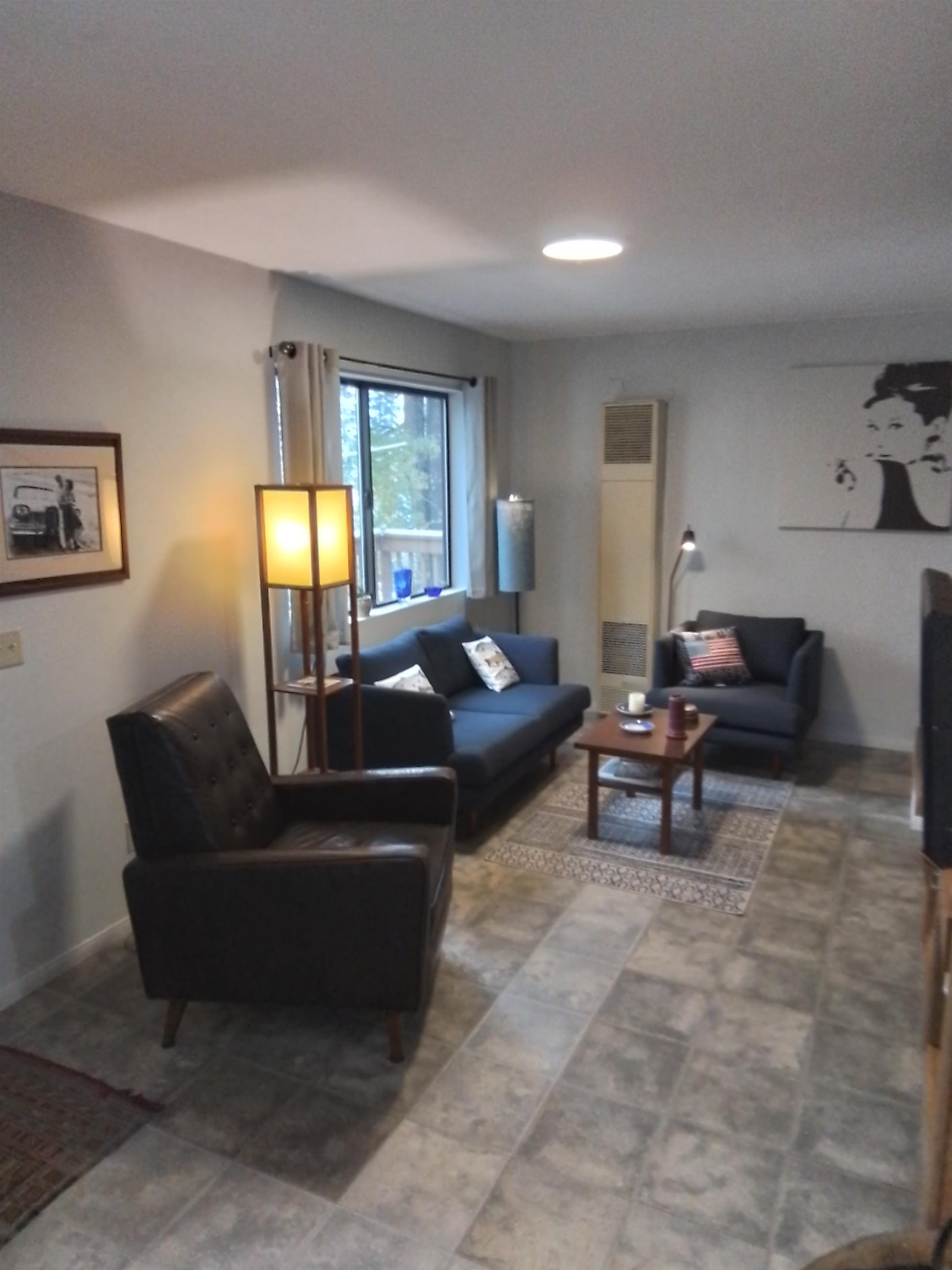 199 Hunewill Drive Bridgeport, CA 93517 - Photo 7 of 40 Living area featuring large format gray tile flooring, a window with outdoor tree scenery, and a wall-mounted heating unit