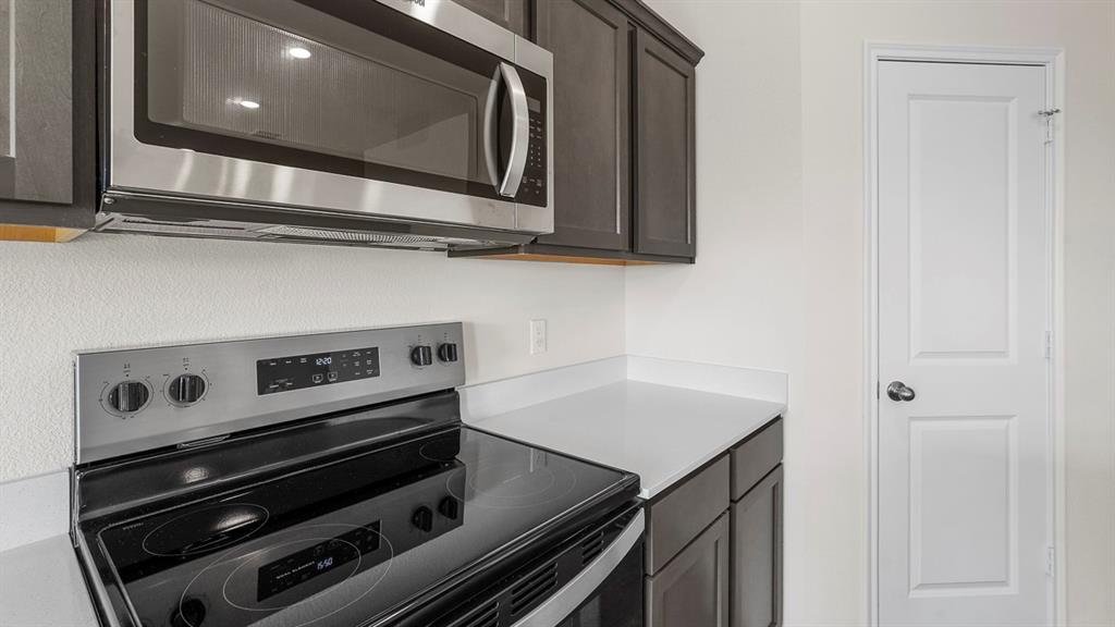1675 Mantle Road Crandall, TX 75114 - Photo 6 of 27 Kitchen featuring stainless steel range and microwave, dark wood-finish cabinetry, and light-toned countertops