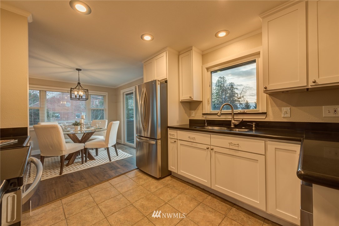 4314 Southwest Frontenac Street Seattle, WA 98136 - Photo 12 of 32 a kitchen with stainless steel appliances granite countertop a refrigerator a sink dishwasher a dining table and chairs with wooden floor