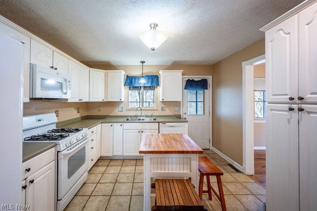 3601 River Road Vienna, WV 26105 - Photo 8 of 40 Kitchen with white appliances, decorative light fixtures, a textured ceiling, white cabinetry, and light tile patterned flooring