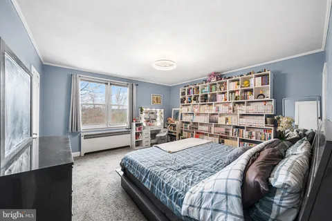 a bedroom with a bed a dresser and a large window