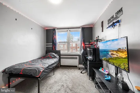 a bedroom with bed and a flat tv screen on the dresser