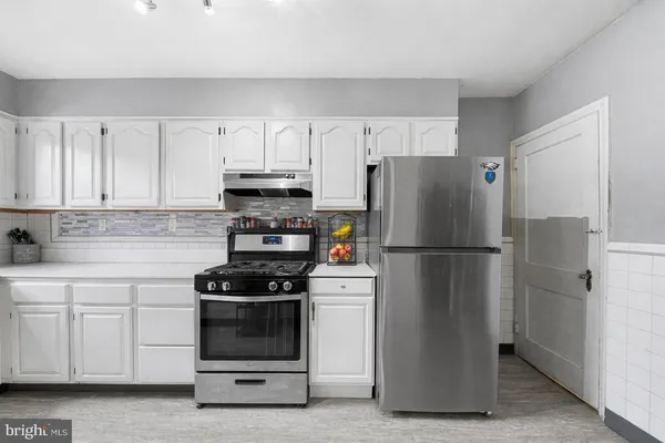 a kitchen with a refrigerator stove and white cabinets