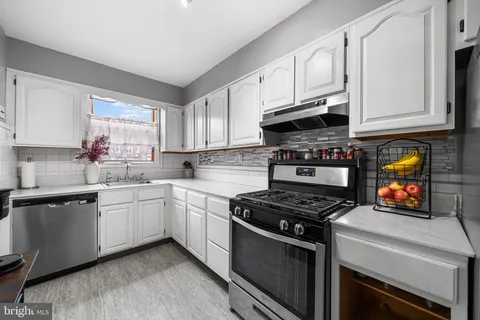 a kitchen with stainless steel appliances granite countertop a stove a sink and a white cabinets