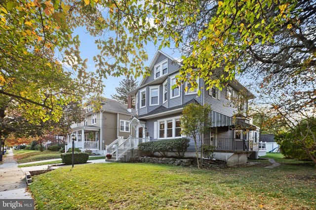 a view of a brick house with a big yard plants and large trees