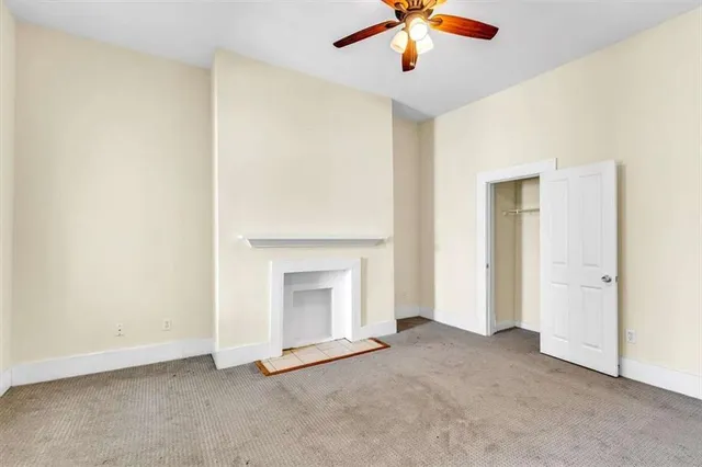 an empty room with a fireplace and chandelier fan