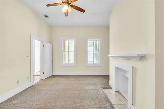 a view of an empty room with chandelier fan and fire place