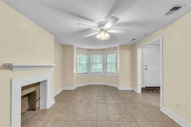 a view of an empty room with chandelier fan and fire place