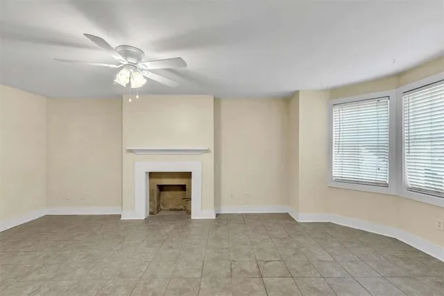 an empty room with chandelier fan and fireplace