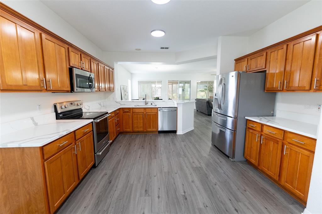 12855 Southeast 92nd Court Road Summerfield, FL 34491 - Photo 14 of 61 a large kitchen with stainless steel appliances granite countertop wooden floors a stove a sink and a white cabinets with wooden floor