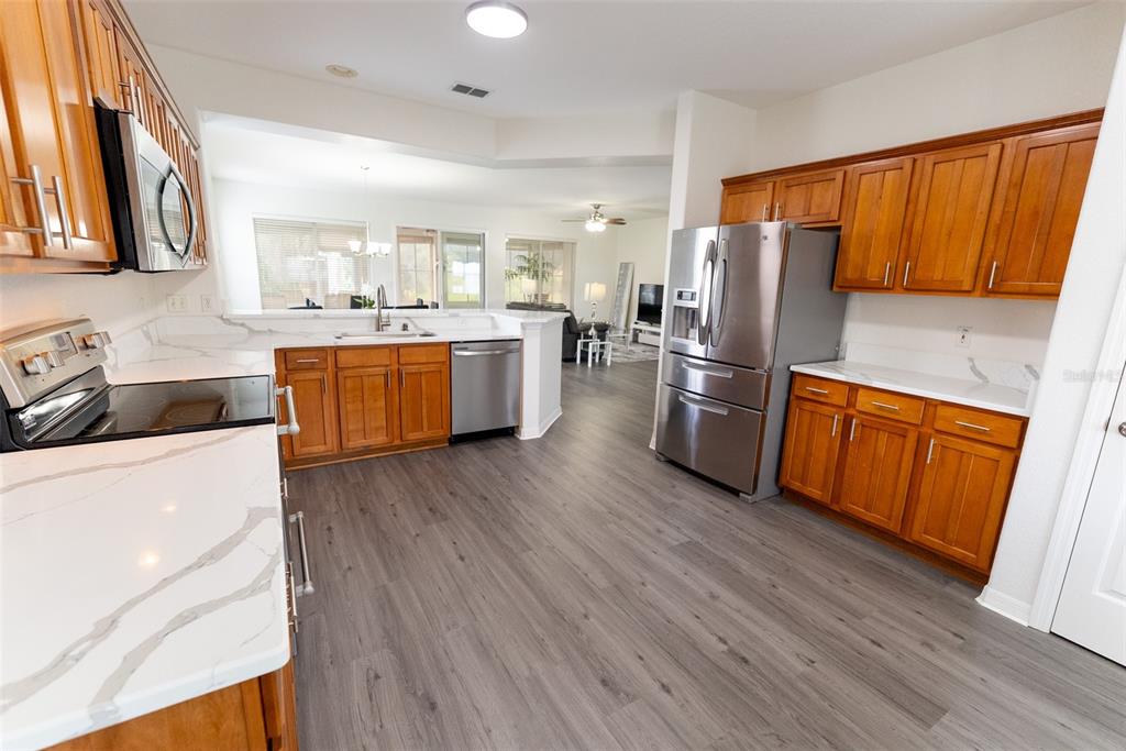 12855 Southeast 92nd Court Road Summerfield, FL 34491 - Photo 15 of 61 a kitchen with stainless steel appliances wooden floors and wooden cabinets