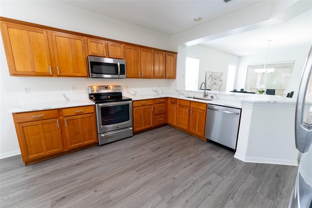 12855 Southeast 92nd Court Road Summerfield, FL 34491 - Photo 16 of 61 a kitchen with stainless steel appliances granite countertop wooden floors and white cabinets
