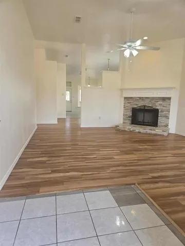 a view of an empty room with wooden floor and a fireplace