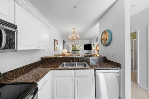 a kitchen with granite countertop a sink a stove and cabinets