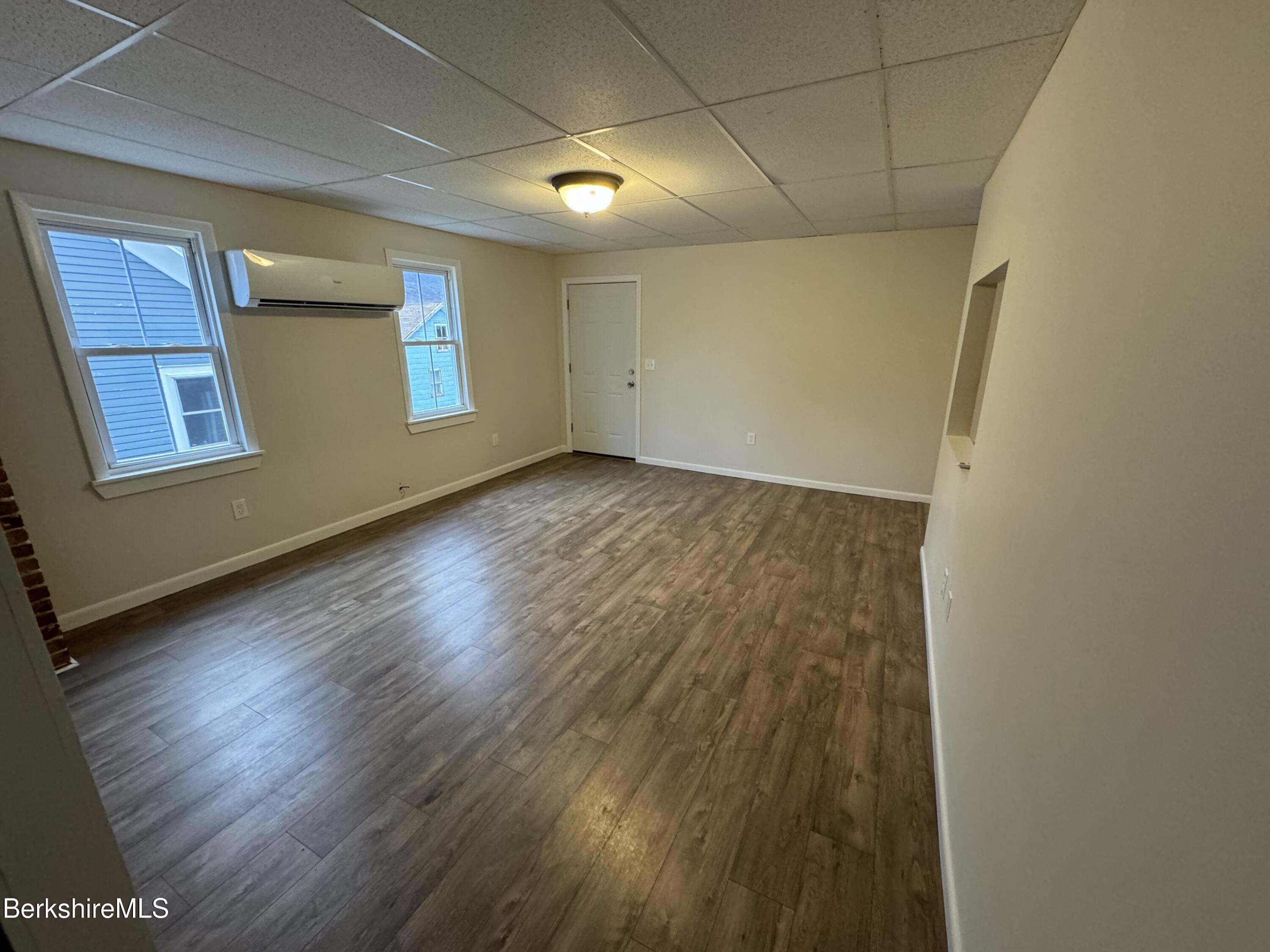 84 Summer Street, Unit B Adams, MA 01220 - Photo 5 of 8 an empty room with wooden floor and windows