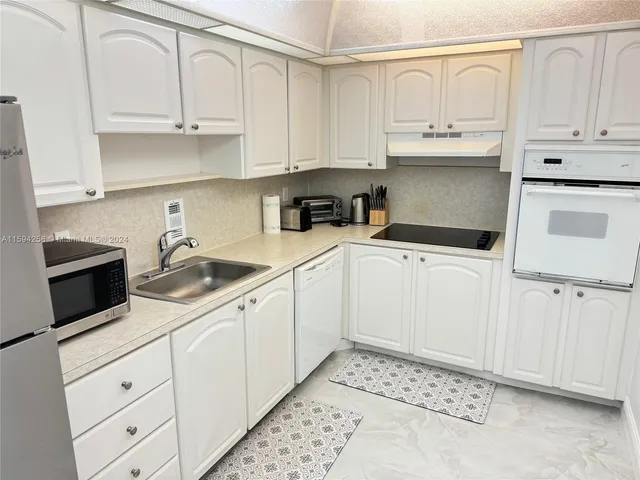a kitchen with white cabinets and white appliances