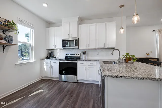 a kitchen with granite countertop a sink cabinets and stainless steel appliances