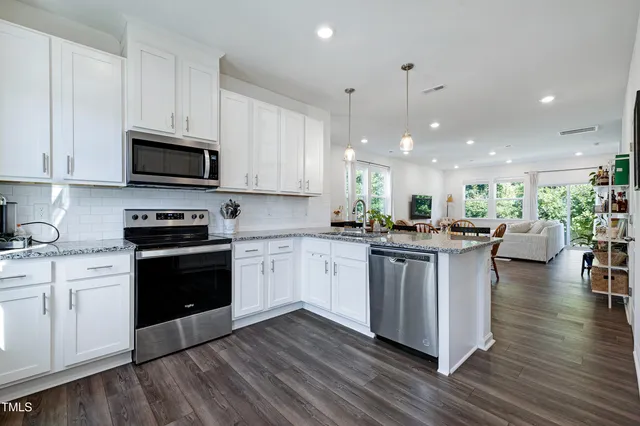 a kitchen with kitchen island granite countertop a stove top oven a sink a counter space and cabinets