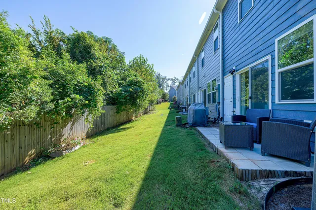 a view of a patio with couches plants and large trees