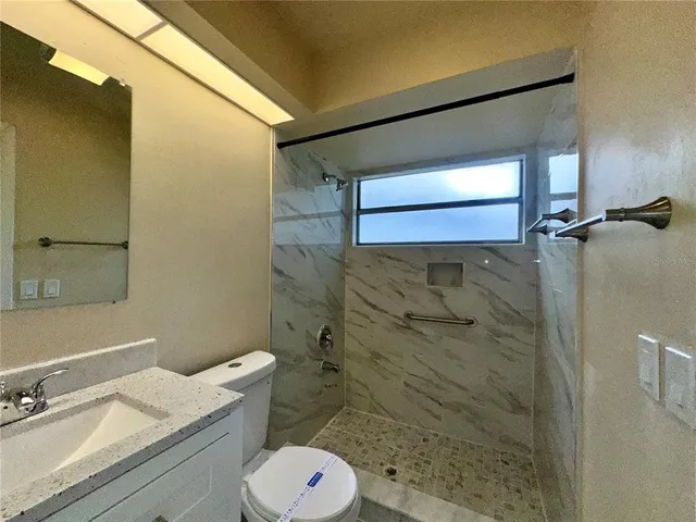 a bathroom with a granite countertop sink toilet and shower
