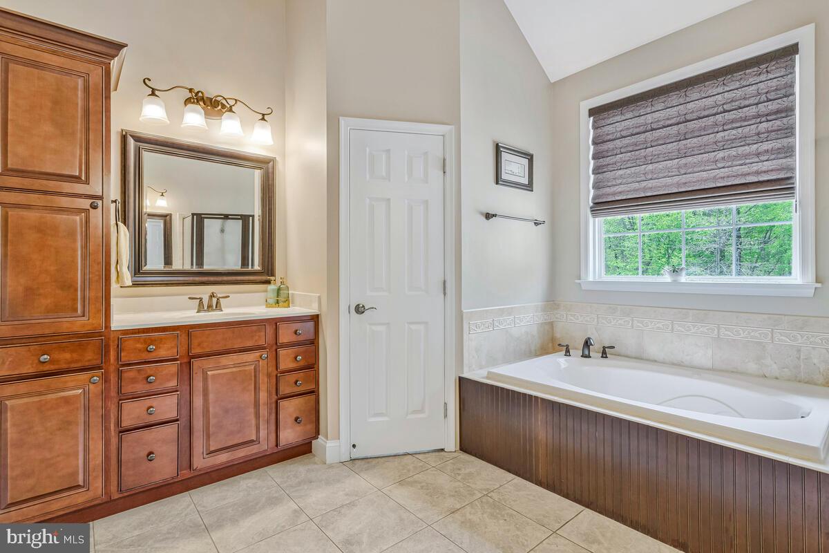 2720 Emmanuel Church Road Huntingtown, MD 20639 - Photo 27 of 85 a spacious bathroom with a double vanity sink a large mirror and a bathtub